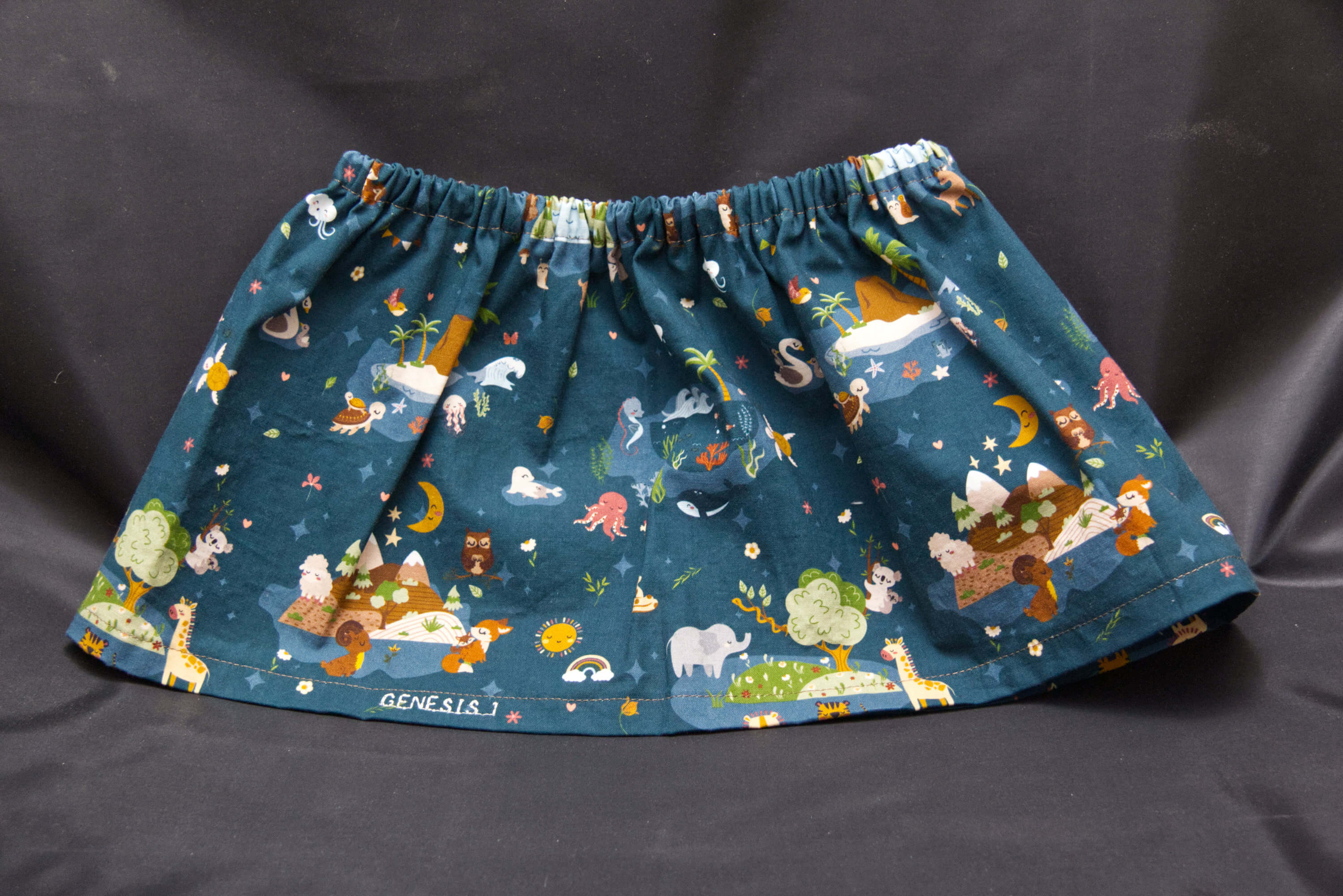 A blue skirt with animals, birds, sea creatures and nature scenes on it.