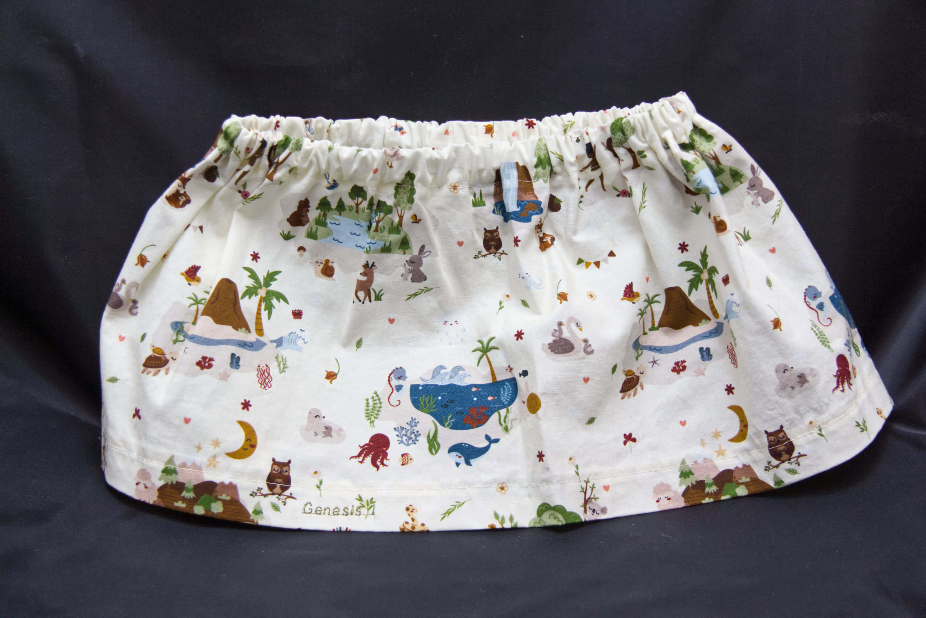 A white skirt with animals, birds, sea creatures and nature scenes on it.